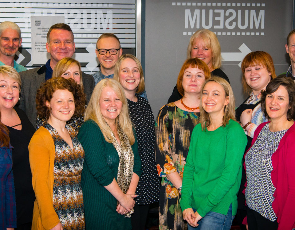 Curious Minds Team. A large group of people from a range of ages and hairstyles - predominantly women and all smiling!
