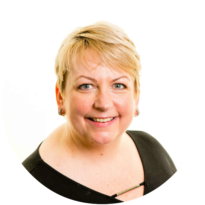 Image shows head and shoulders portrait of Derri Burdon. Derri has short blonde hair. She is smiling.