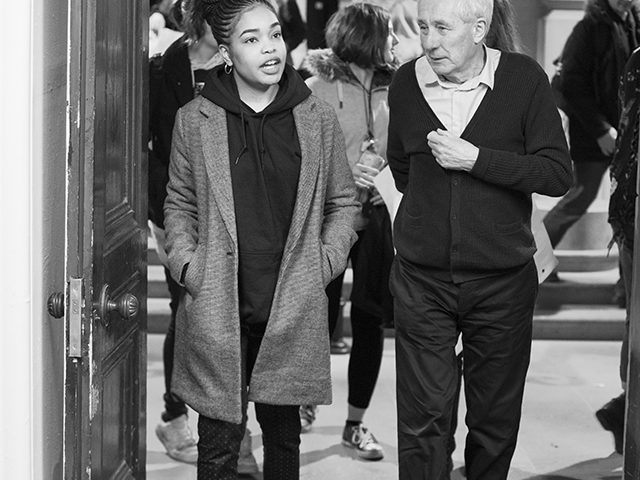A young adult and older male walk through a cultural venue deep in discussion