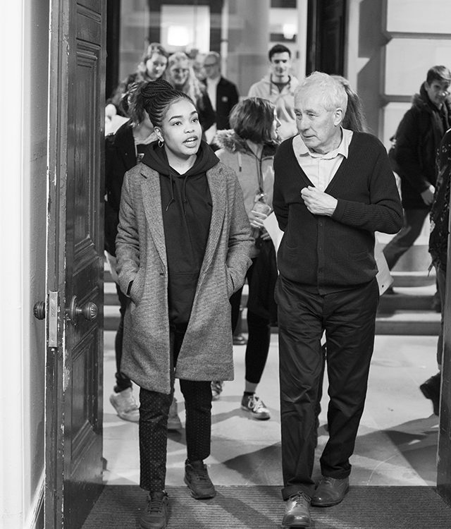 A young adult and older male walk through a cultural venue deep in discussion