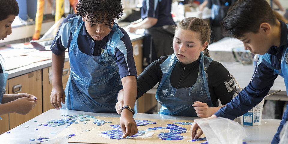 4 school children doing art in a classroom.
