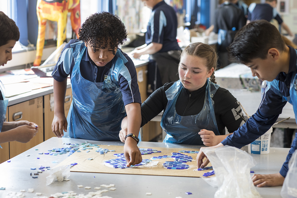 4 school children doing art in a classroom.