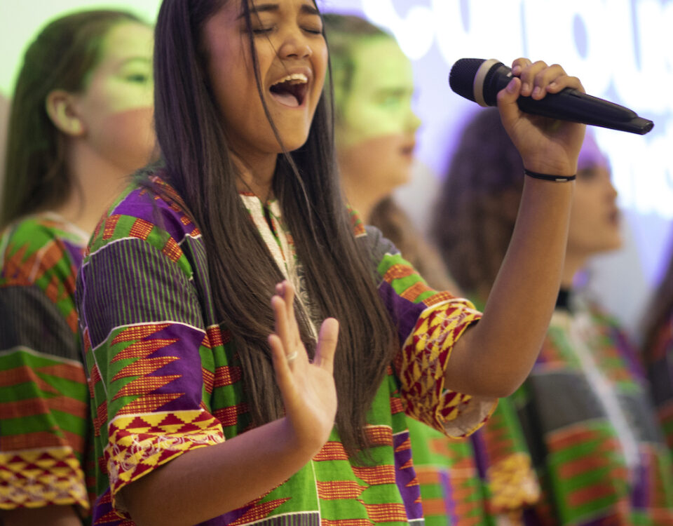Young person holding microphone enjoys performing with other choir members
