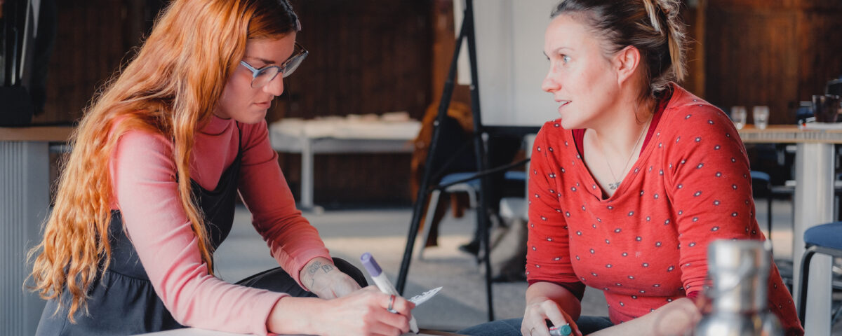 Two people are sat at a desk in discussion