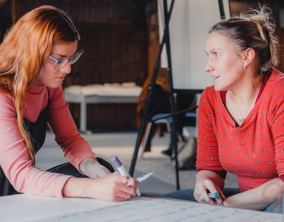 Two people are sat at a desk in discussion