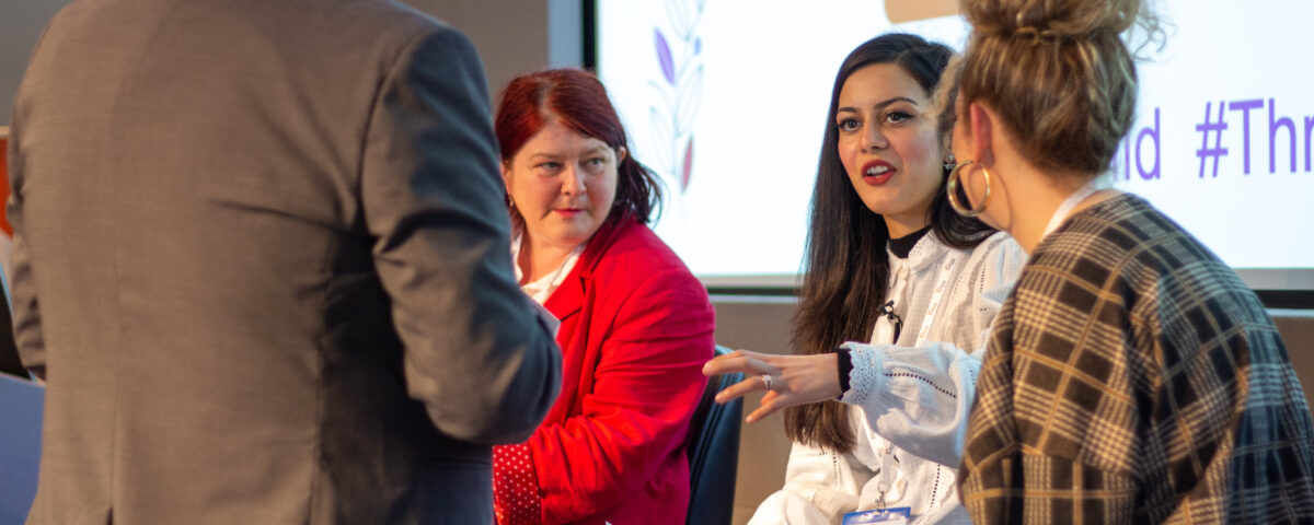3 people listening to a young woman describe something.