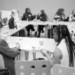 A group of young people engaged in conversations around a table.