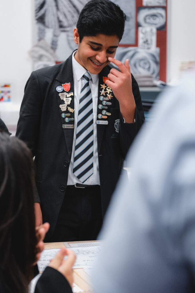 A Key Stage 3 school student in uniform works at a computer